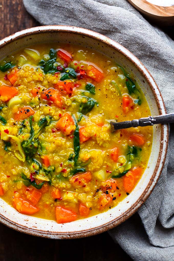 Indisches Rote Linsen-Curry in einer beigen Steingut-Schüssel mit einem grauen Leinentuch im Hintergrund.