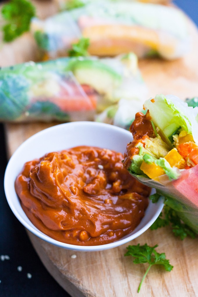 Werbung. Schnelle Summer Rolls mit Erdnusssauce aus vier Zutaten. Frisch, knackig und gesund! Perfekt als leichtes Abendessen und zum Mitnehmen - kochkarussell.com Fertige, an einer Seite offene, Summer Roll lehnt an einer weißen, kleinen Schüssel mit Erdnusssauce. Die vietnamesische Sommerrolle wurde in die Erdnusssauce getunkt.