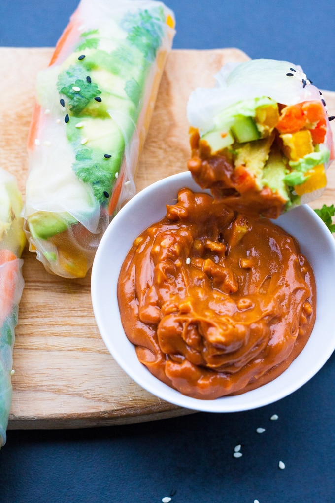 Werbung. Summer Rolls mit schneller Erdnusssauce. Frisch, knackig und gesund! Perfekt als leichtes Abendessen und zum Mitnehmen - kochkarussell.com Fertige, an einer Seite offene, Summer Roll lehnt an einer weißen, kleinen Schüssel mit Erdnusssauce. Die vietnamesische Sommerrolle wurde in die Erdnusssauce getunkt. Daneben ist noch eine weitere fertige Summer Roll zu sehen.