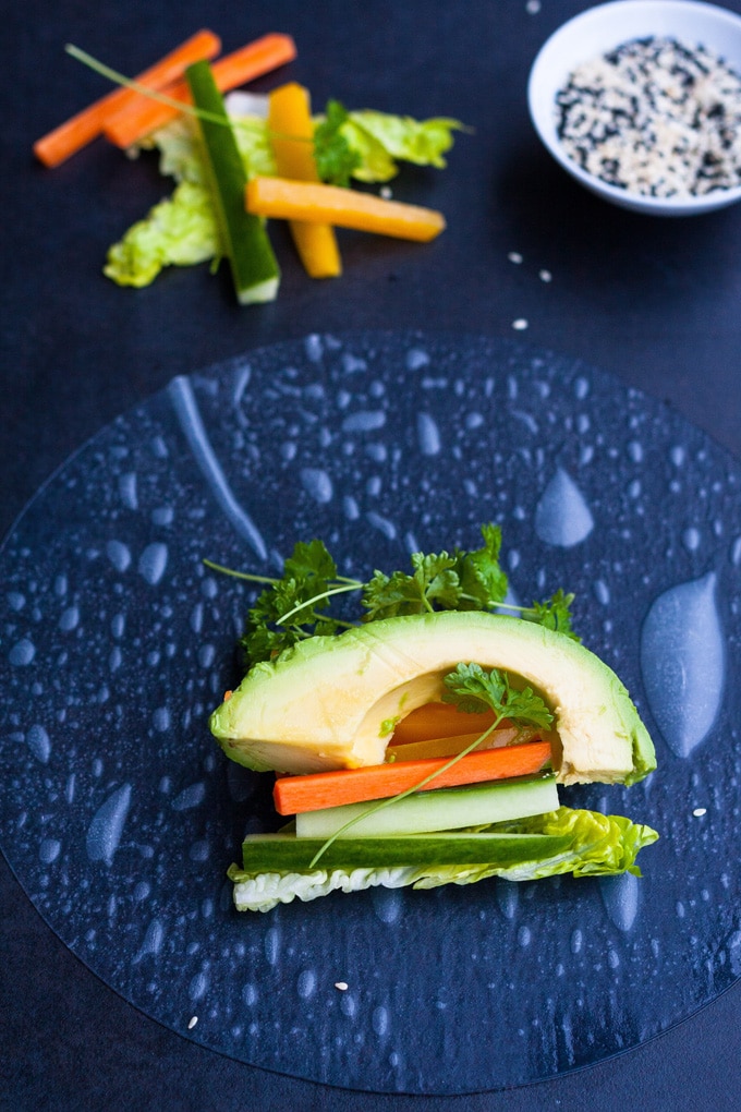 Werbung. Summer Rolls mit schneller Erdnusssauce. Frisch, knackig und gesund! Perfekt als leichtes Abendessen und zum Mitnehmen - kochkarussell.com Zutaten für die schnellen Summer Rolls auf einem eingeweichten Reispapier. ZU sehen sind Avocado, Karotte, Gurke, Salat und Petersilie.