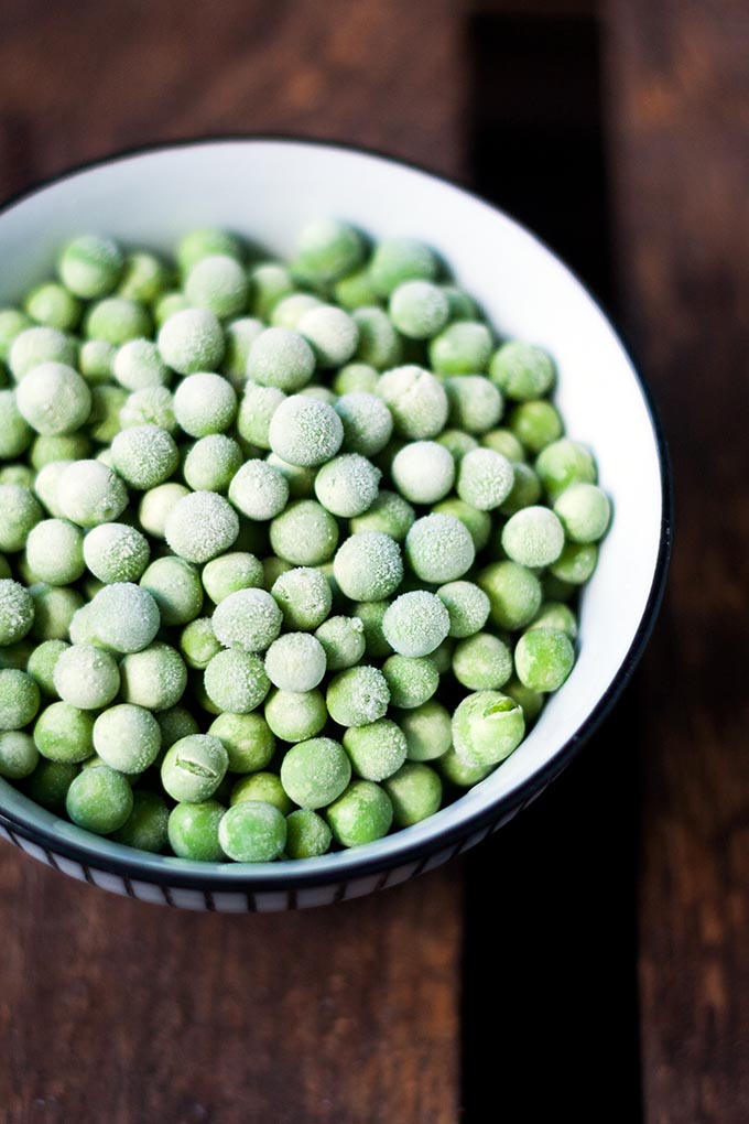 20-Minuten Thai Green Curry Soup. Dieses 10-Zutaten Rezept ist herzhaft, würzig und schnell gemacht. Das perfekte, dampfende Soulfood nach einem langen Tag - kochkarussell.com TK-Erbsen in einer Schüssel auf dunklem Holzuntergrund.