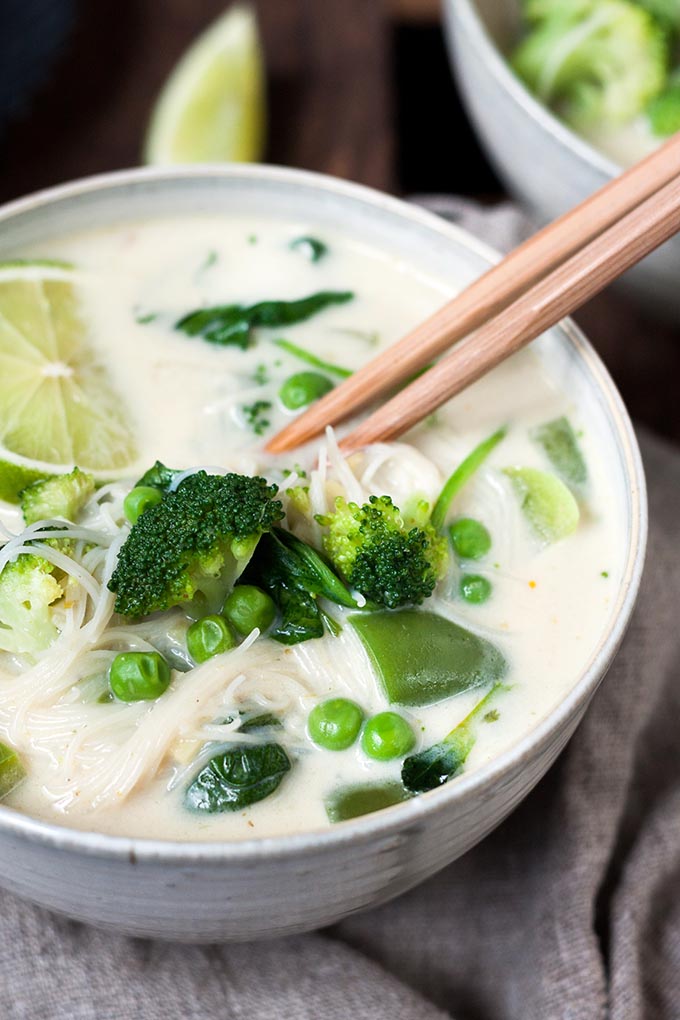 20-Minuten Thai Green Curry Soup. Dieses 10-Zutaten Rezept ist herzhaft, würzig und schnell gemacht. Das perfekte, dampfende Soulfood nach einem langen Tag - kochkarussell.com Fertige 20-Minuten Thai Green Curry Soup in einer großen grau-weißen Schüssel und zwei hellbraunen Ess-Stäbchen