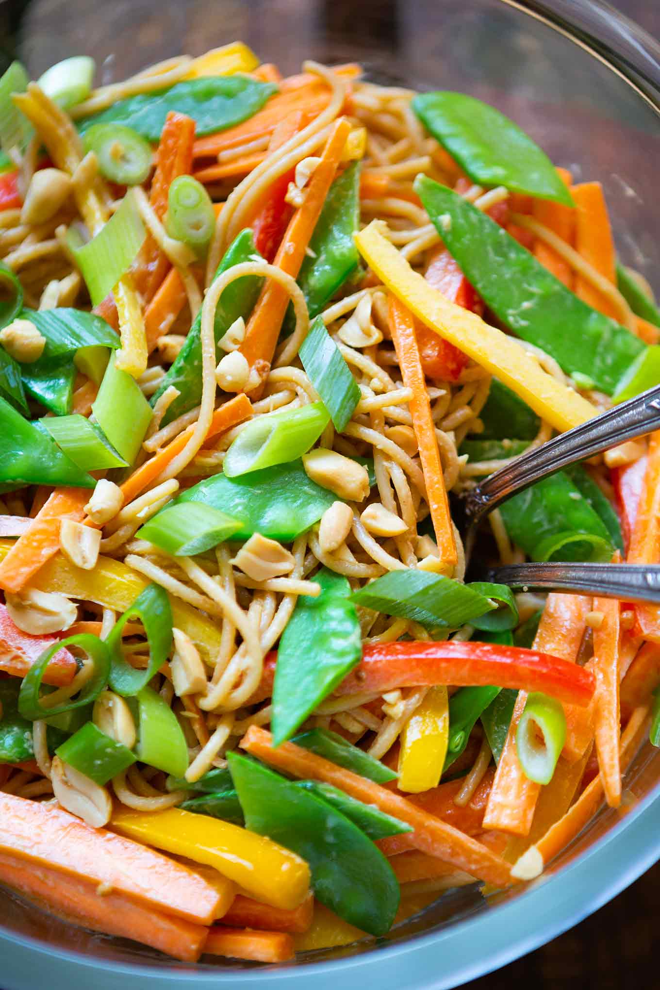 Fertiger Nudelsalat in einer Glasschüssel mit Löffel und Gabel.