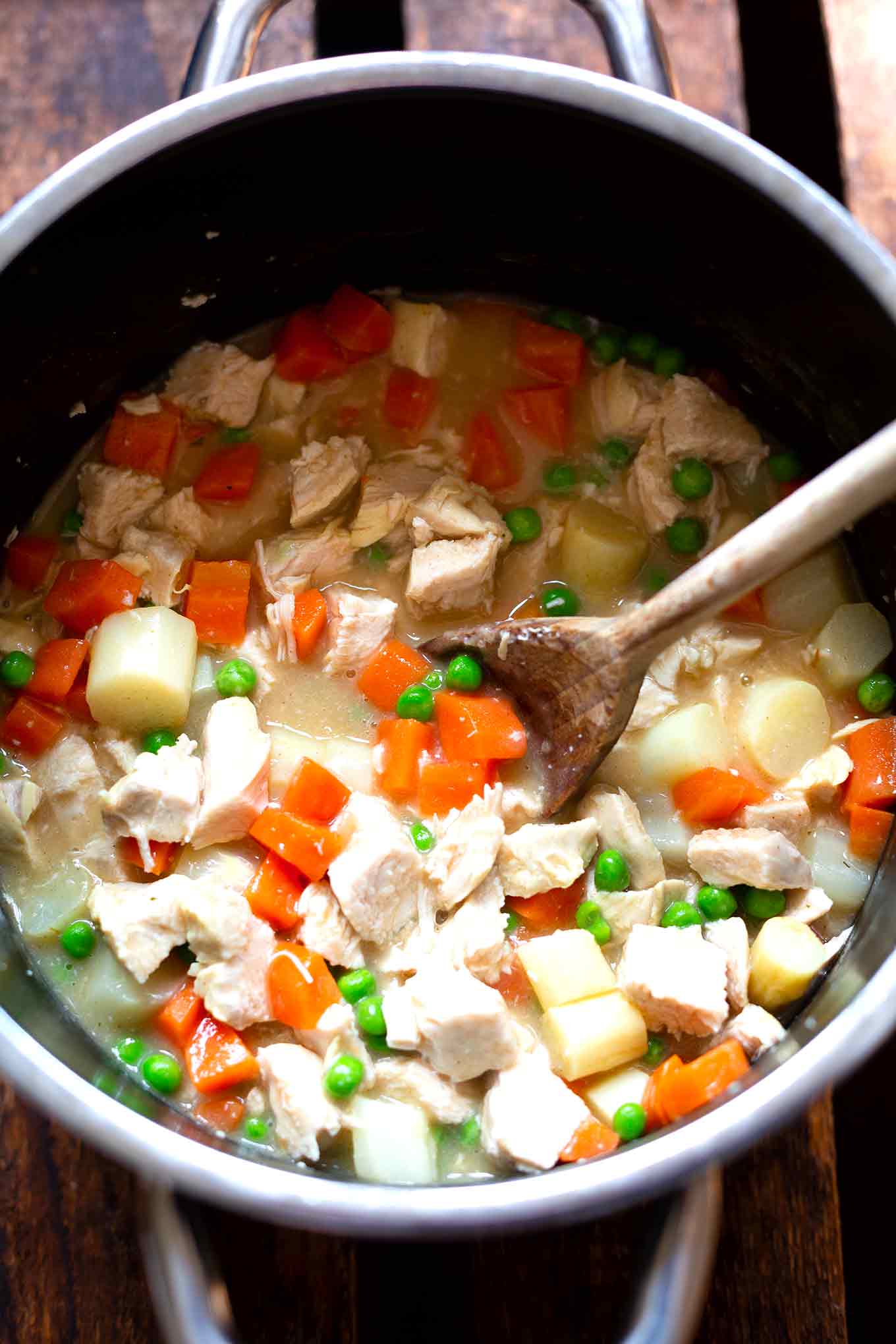 Hühnerfrikassee fertig gekocht im Kochtopf mit einem Holzlöffel.