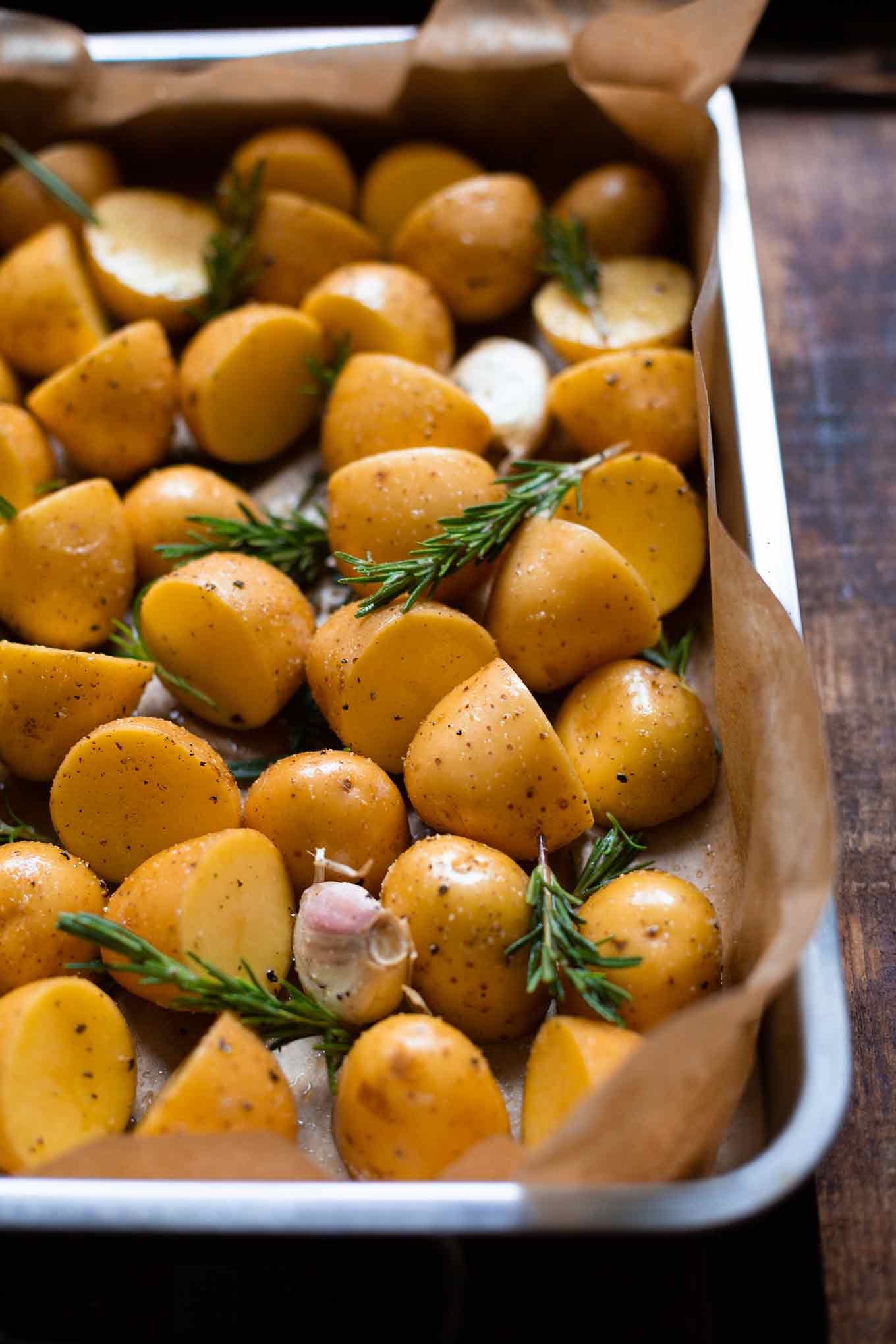 Blech mit Rosmarinkartoffeln und Knoblauch, bevor sie in den Backofen geschoben werden.
