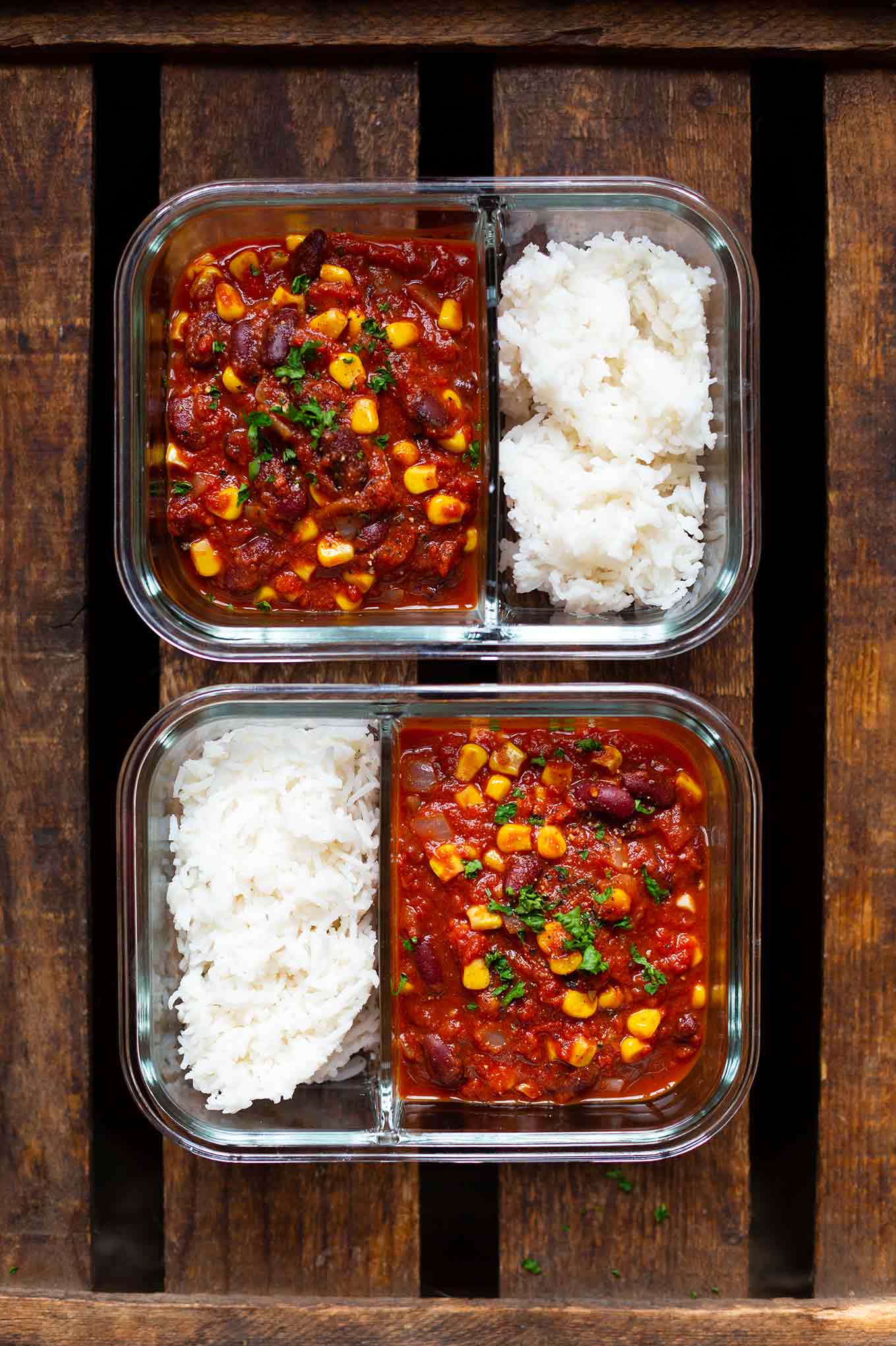 Chili sin Carne als Meal Prep in zwei Glasschüsseln mit Trennsteg verteilt. Chili und Reis werden separat aufbewahrt.