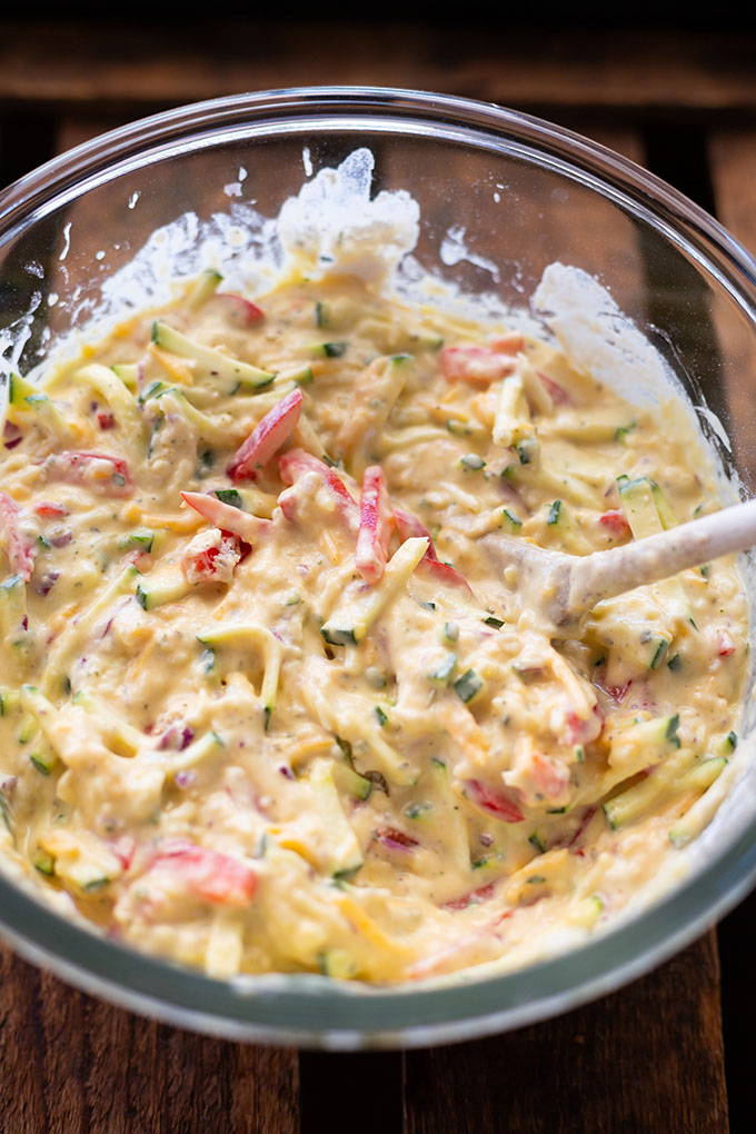 Teig mit allen klein geschnittenen Zutaten für die vegetarische Quiche mit Gemüse in einer Glasschüssel.