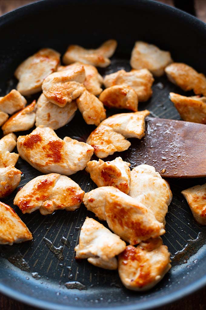 Knusprig angebratenes Hähnchenfleisch für das Nasi Goreng in einer dunklen Pfanne.