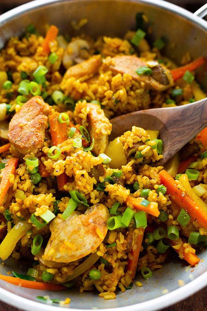 Nasi Goreng fertig gekocht in einer silbernen Edelstahl Pfanne mit einem Kochlöffel.