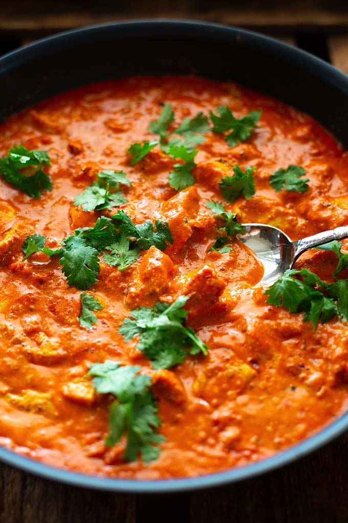 Indisches Butter Chicken mit Basmatireis und Koriander angerichtet in einer großen Servierpfanne.