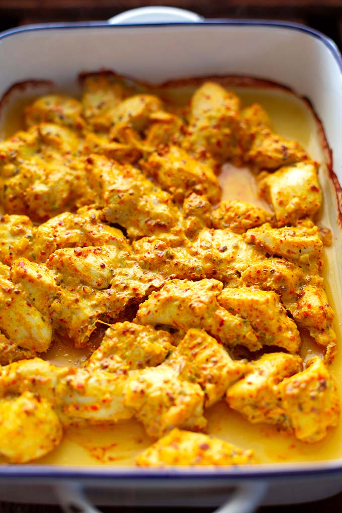 Das marinierte und im Ofen geschmorte Hähnchenfleisch für das Murgh Makhani in einer weißen Emaille-Auflaufform mit blauem Rand.