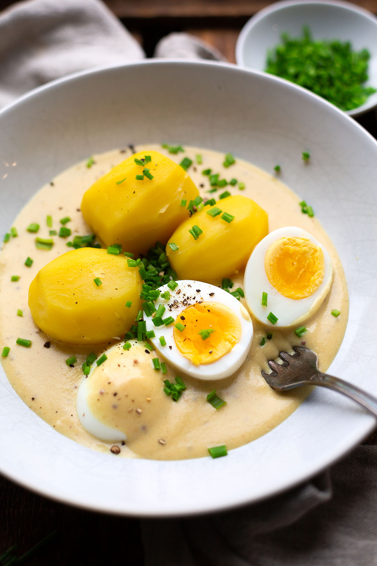 Senfeier mit Kartoffeln nach Omas Rezept auf einem weißen Teller mit Schnittlauch garniert.