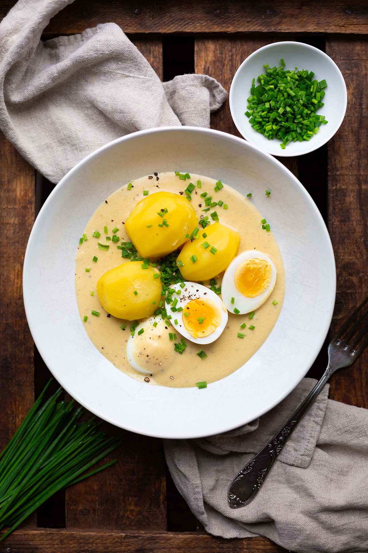 Senfeier mit Kartoffeln nach Omas Rezept auf einem weißen Teller mit Schnittlauch garniert.