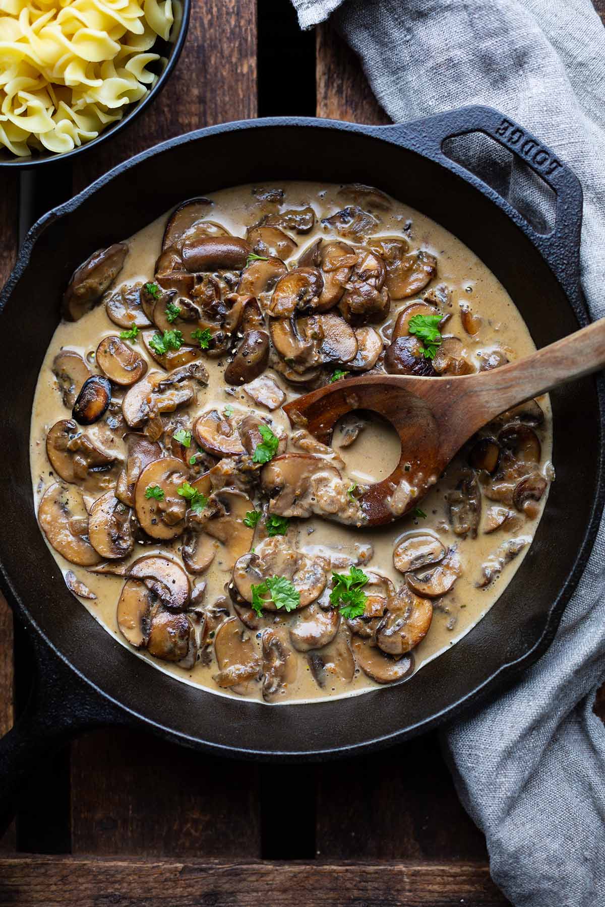 Pilzrahmsoße in schwarzer gusseiserner Pfanne mit Nudeln als Beilage.