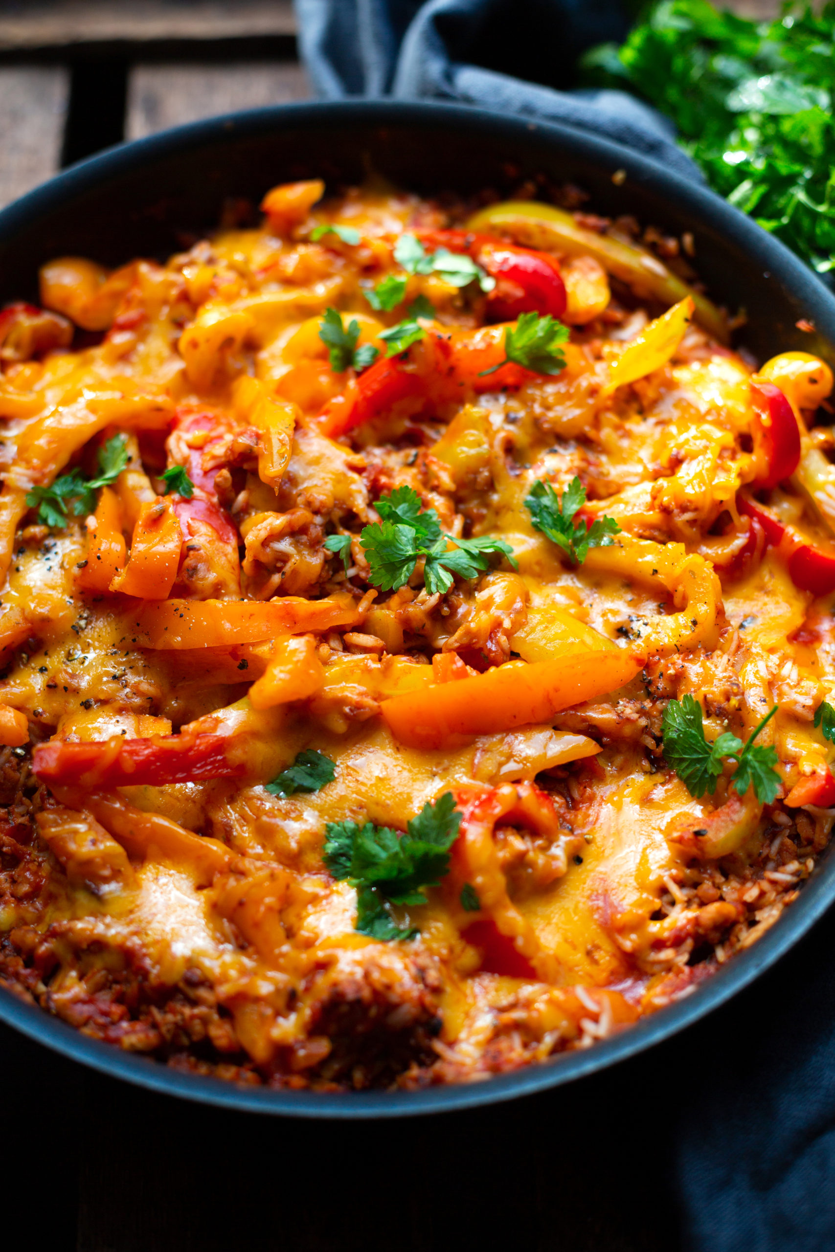 Nahaufnahme Rezeptfotografie vegetarische Paprika-Reispfanne mit Hackfleisch. Abgebildet in einer Pfanne auf einem dunklen Hintergrund.