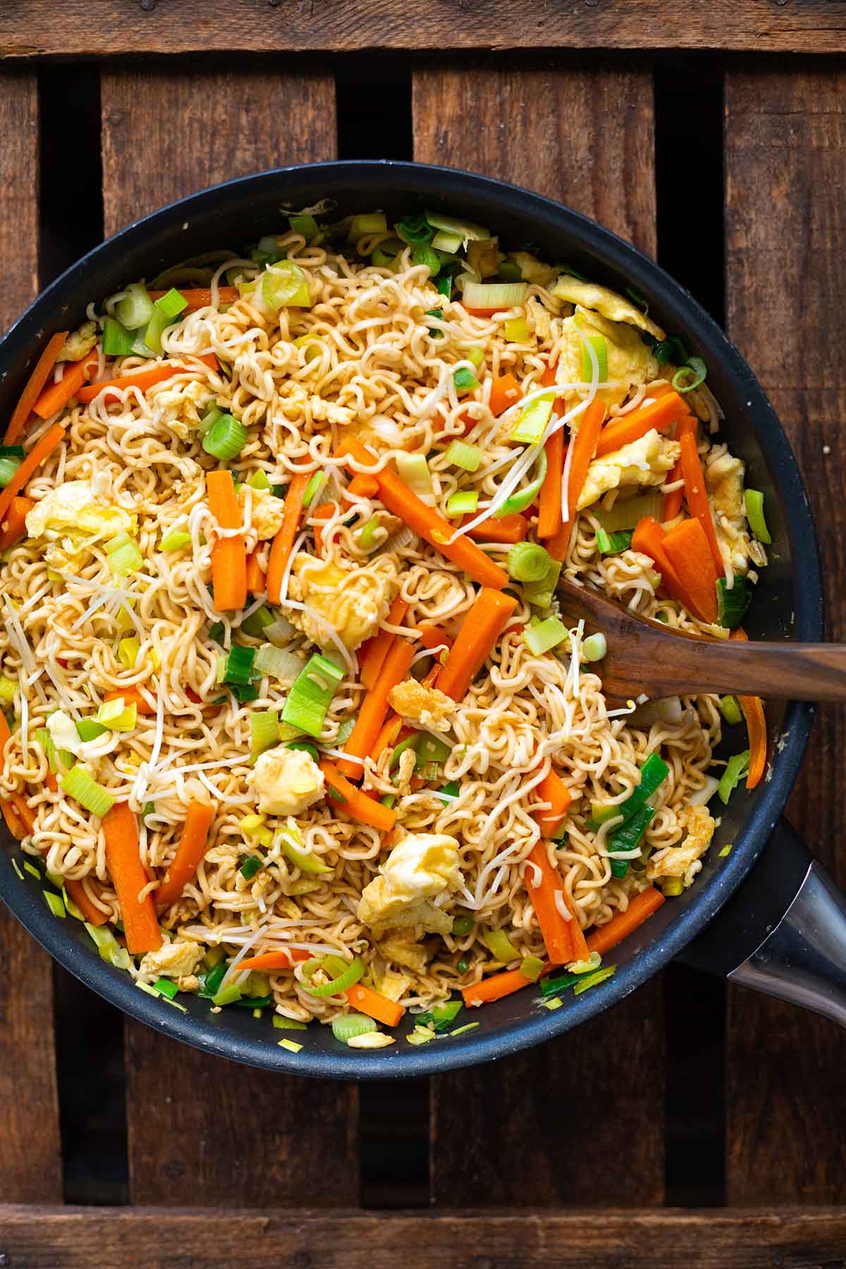 Fertige chinesische gebratene Nudeln mit Gemüse und Ei mit viel Gemüse in fertig gemischt in einer großen Pfanne.