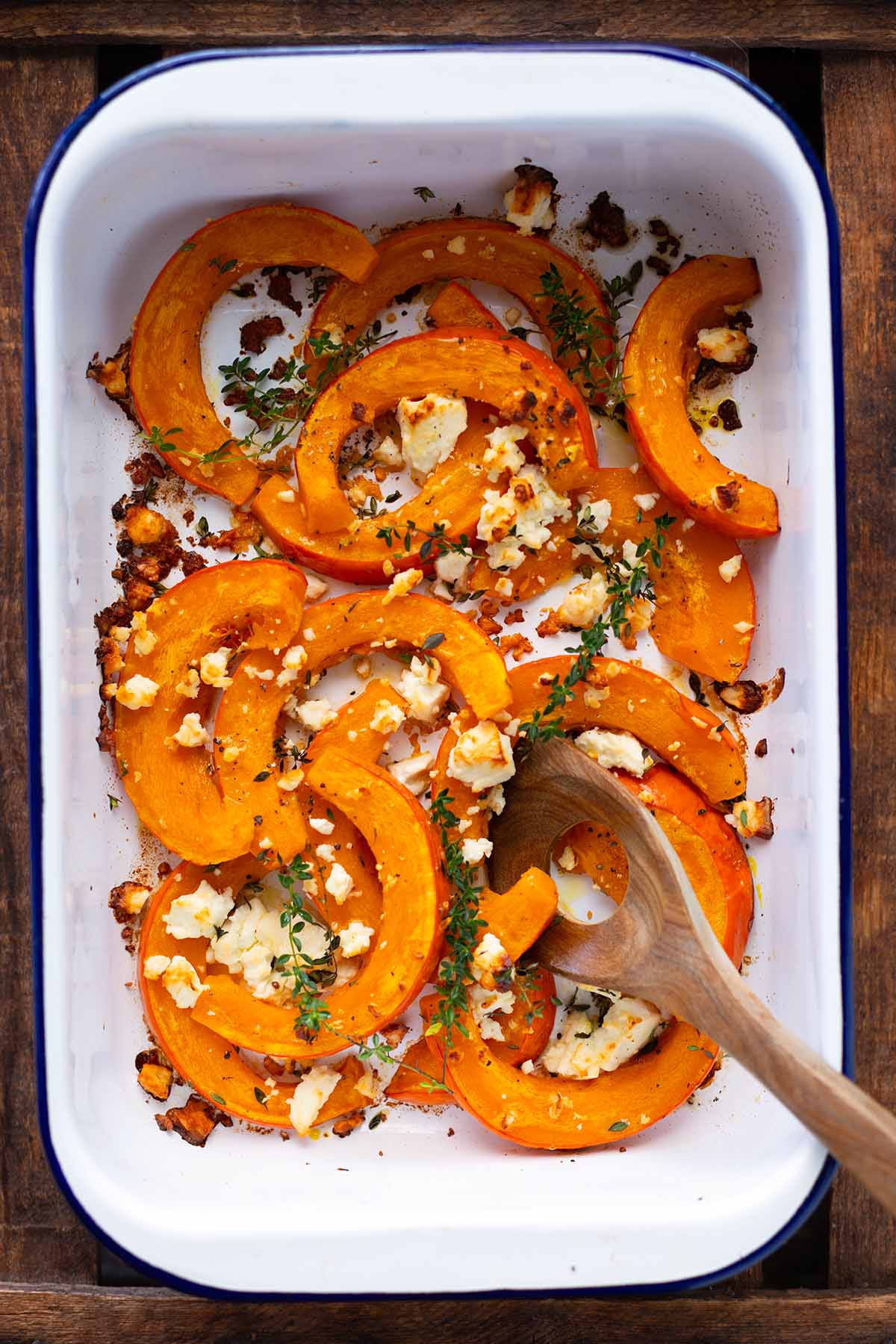 Ofenkürbis mit Feta in einer weißen Auflaufform goldbraun gebacken.