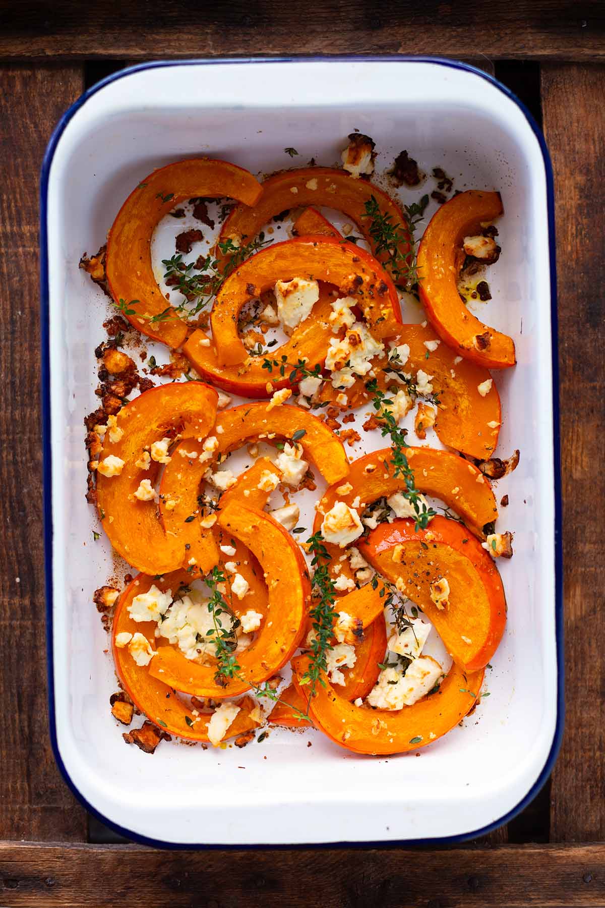 Kürbis aus dem Ofen mit Feta in einer weißen Auflaufform goldbraun gebacken.