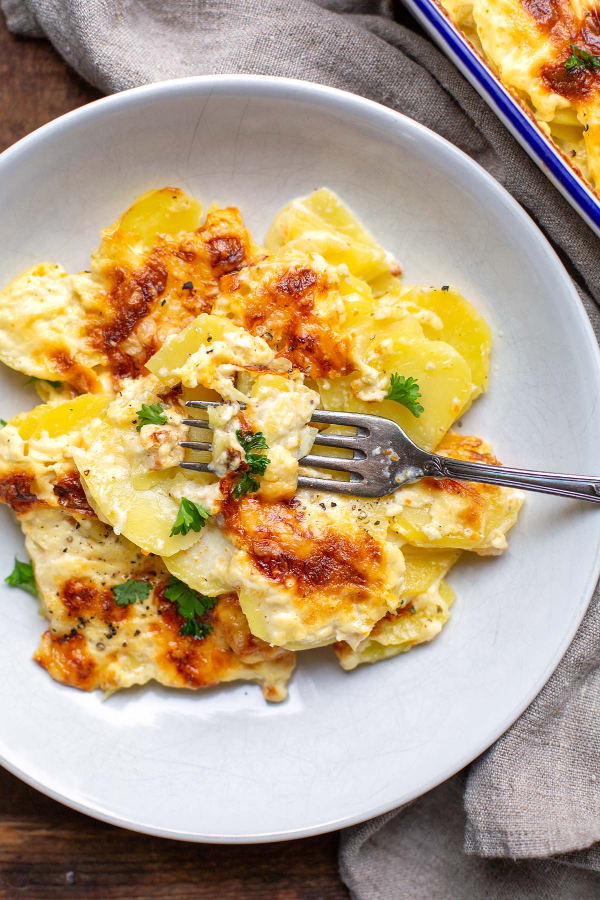 Teller mit einer großen Portion Kartoffelgratin mit Sahne und Käsekruste