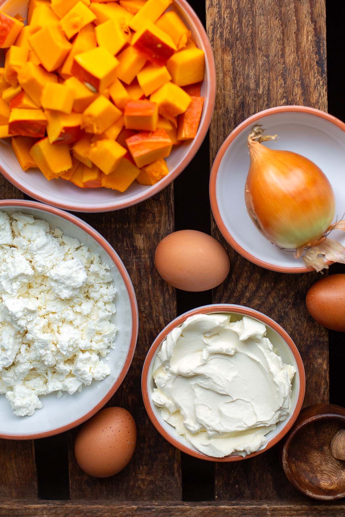 Zutaten für Kürbis-Quiche: Hokkaido Kürbis, Feta, Zwiebel, Eier und Schmand.