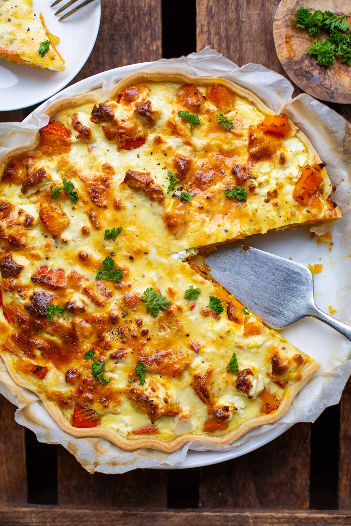 Kürbis-Quiche mit Feta in Quicheform, bestreut mit Petersilie