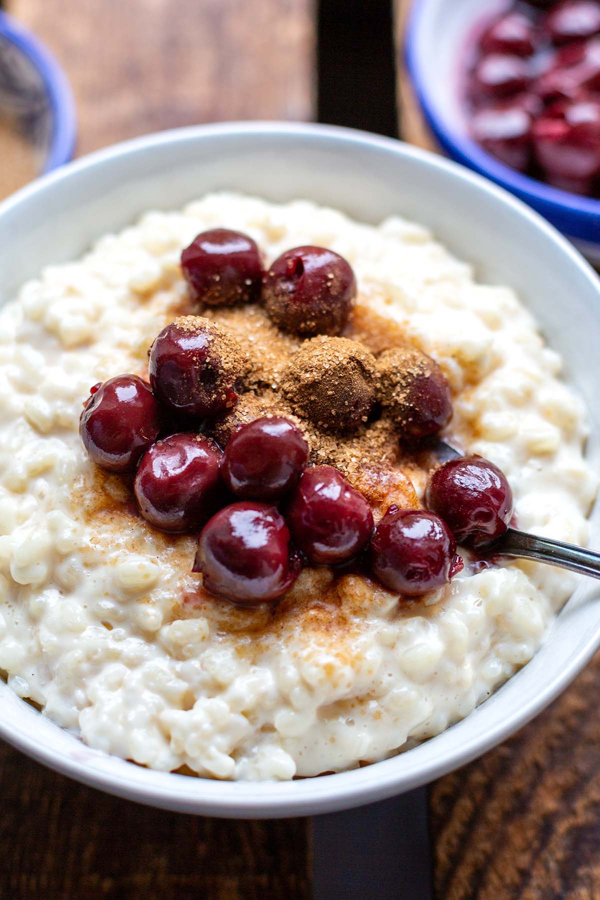 Eine große Portion Milchreis mit Kirschen und Zimt-Zucker in einer weißen Schüssel