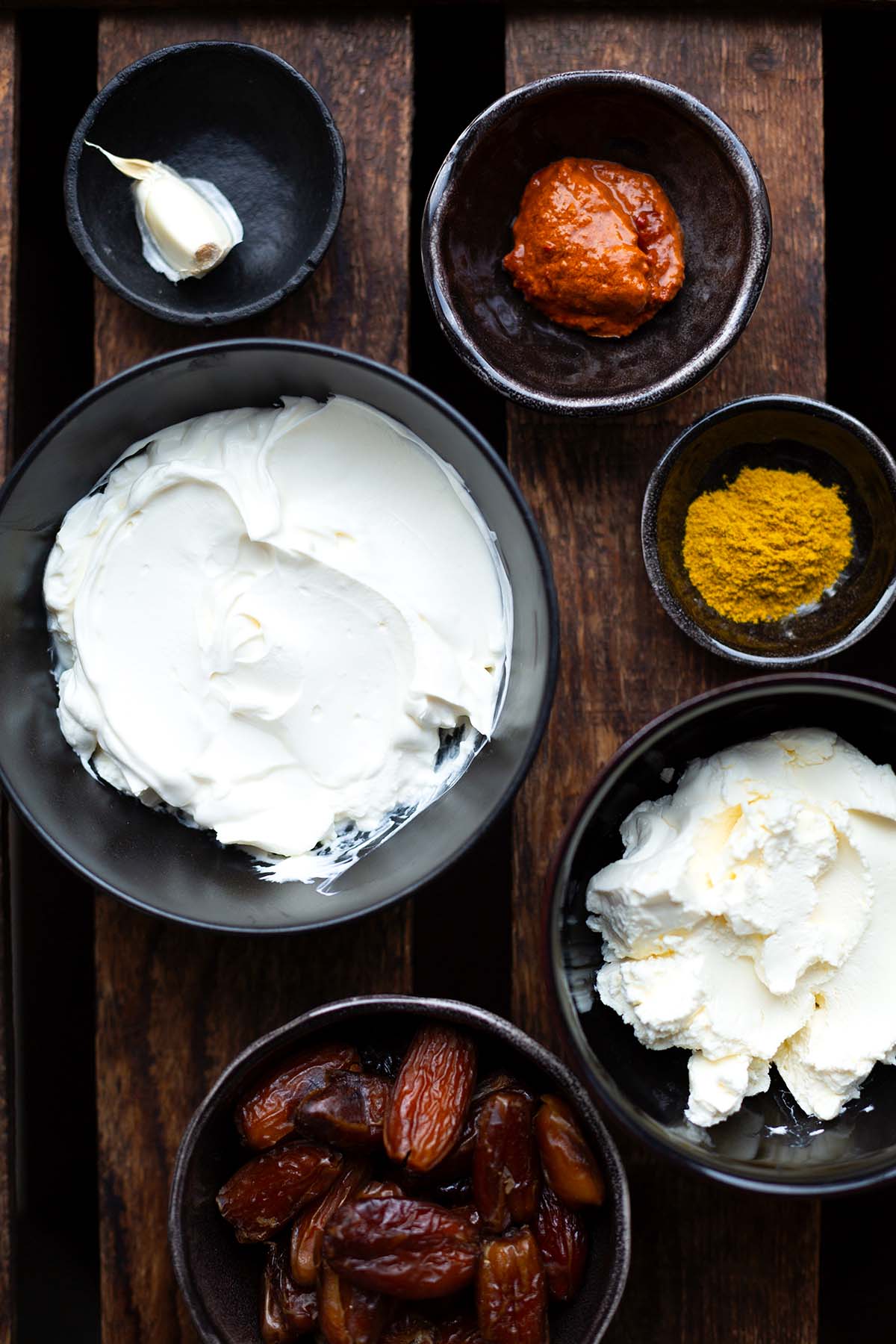 Zutaten für den Datteldip in Schüsseln: Datteln, Frischkäse, Schmand, Currypulver, Harissapaste, Knoblauch