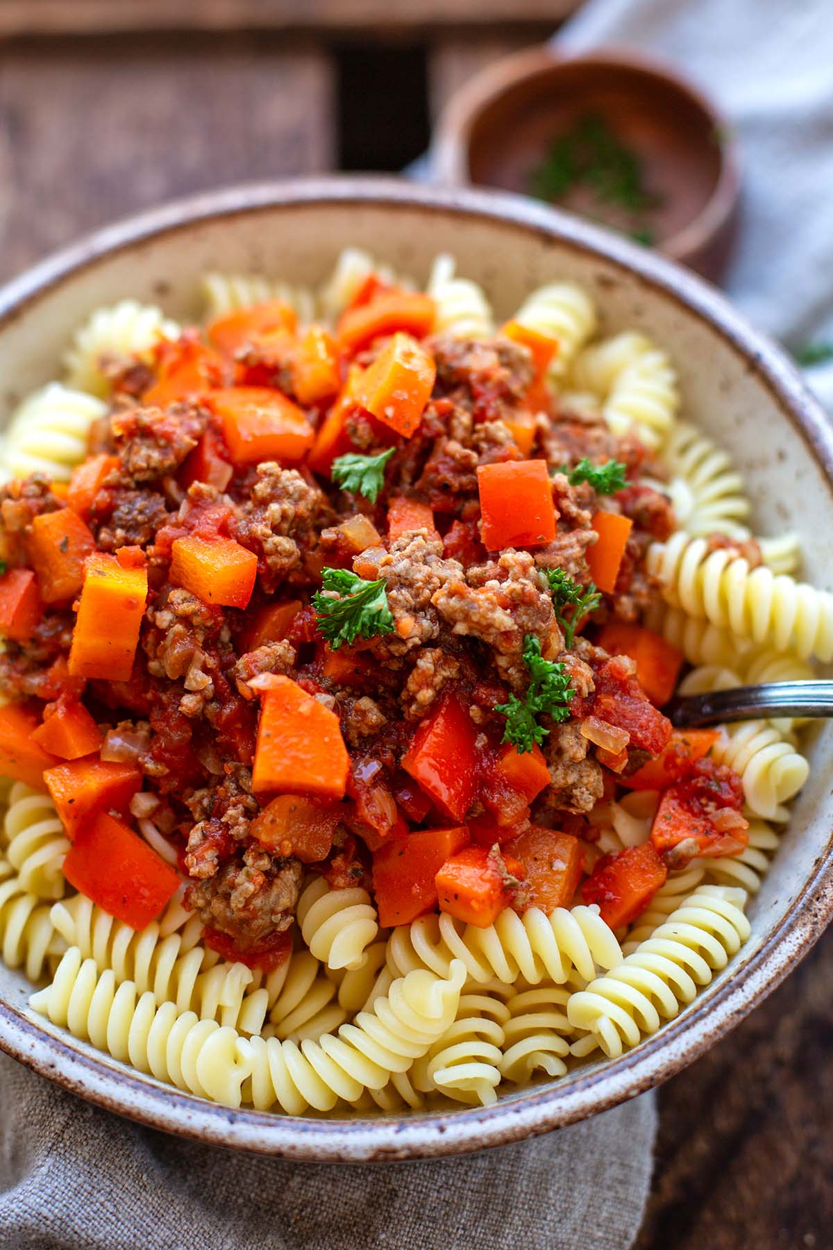 Fertige Hackfleischsoße mit Tomaten mit Fussili-Pasta in einer braunen Steingut Schüssel angerichtet.