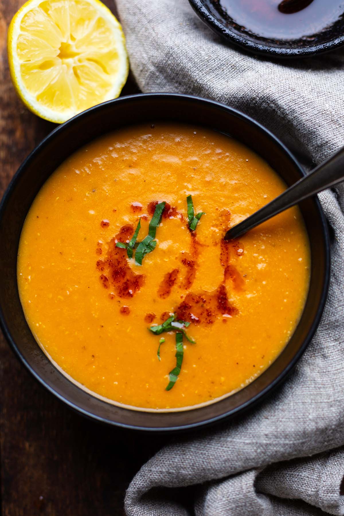 Türkische Linsensuppe in einer schwarzen Schale angerichtet mit Petersilie und Chiliöl garniert.