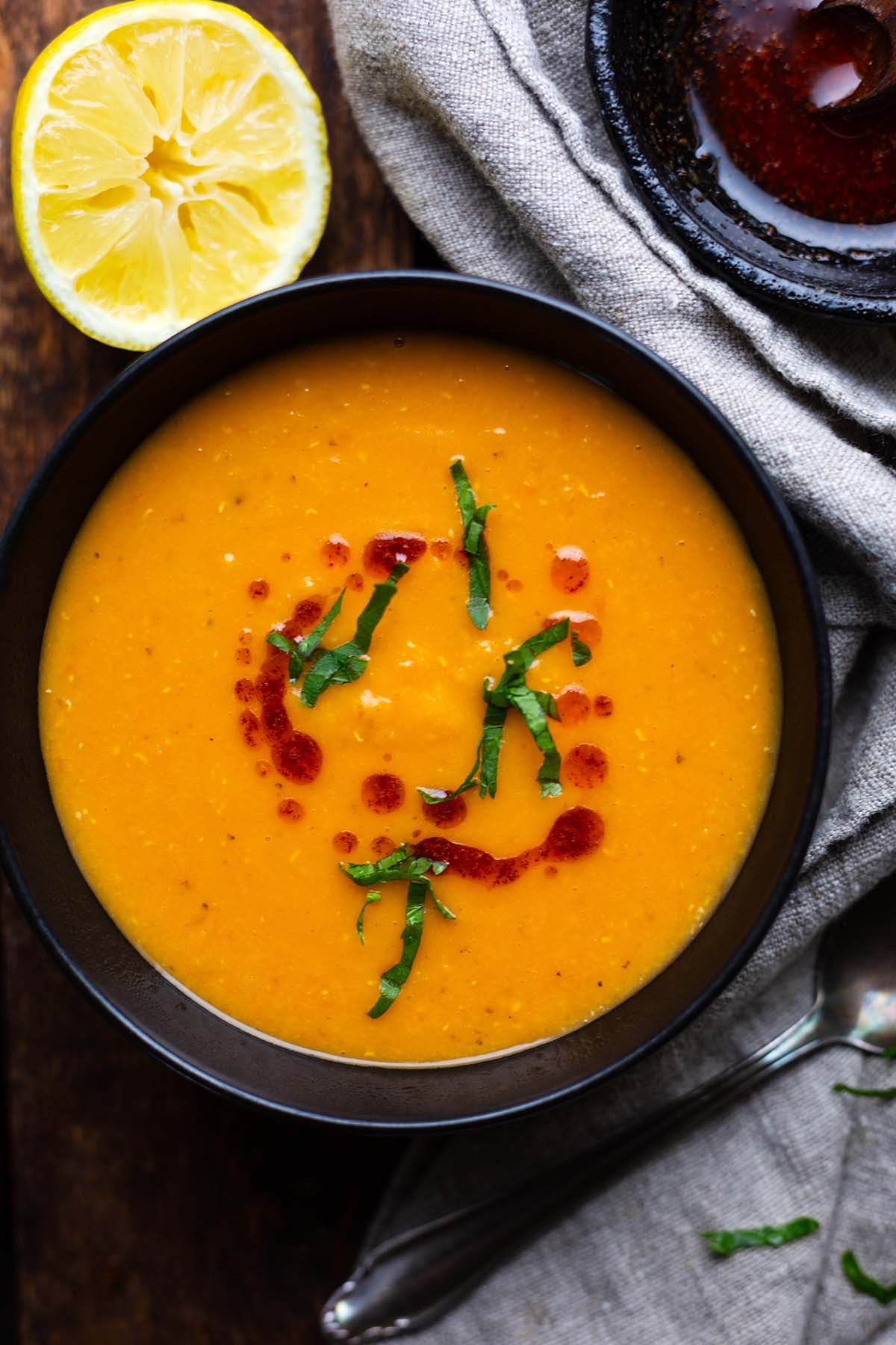 Türkische Linsensuppe in einer schwarzen Schale angerichtet mit Petersilie und Chiliöl garniert.
