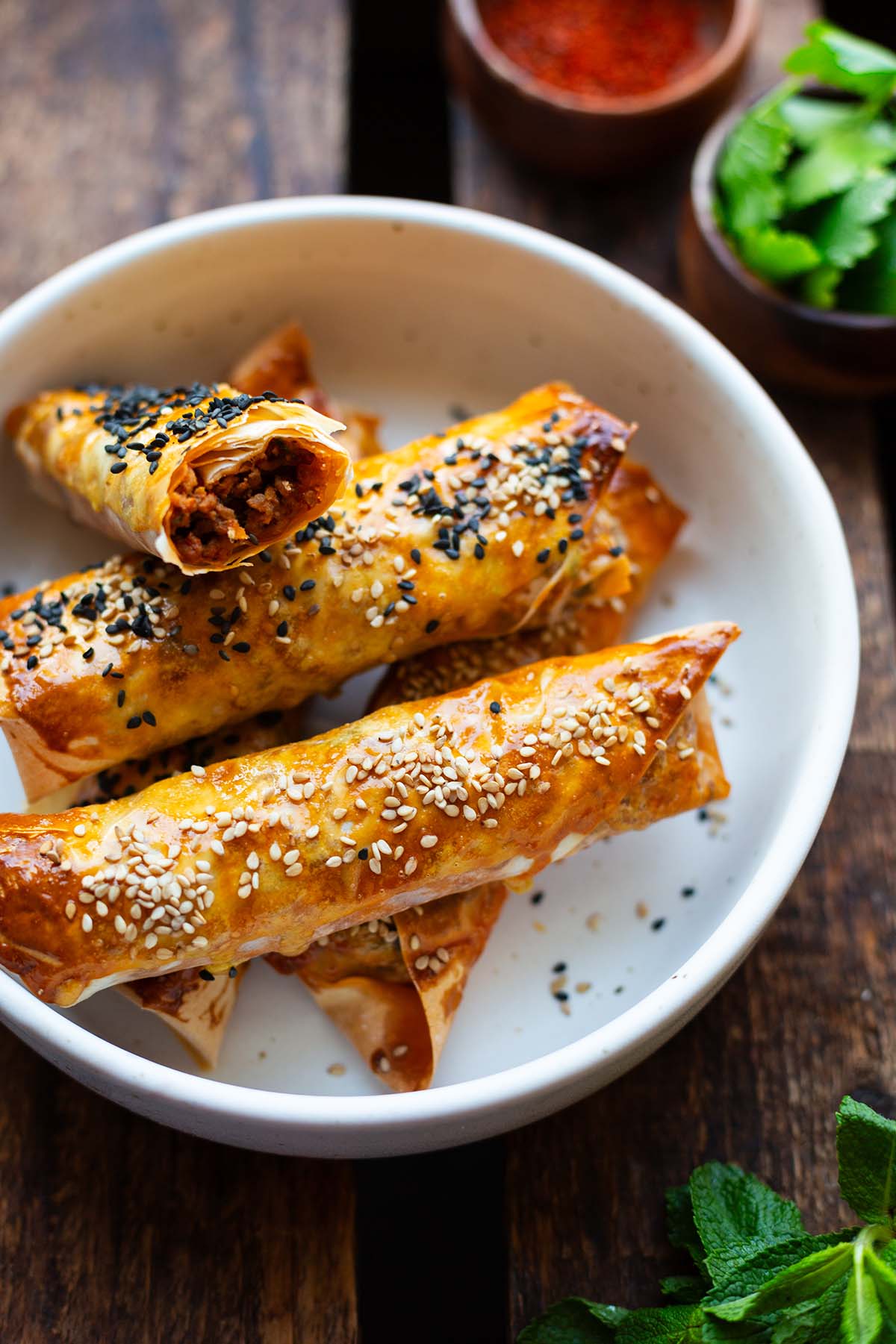Börek mit Hackfleisch und Sesam bestreut auf einem weißen Teller angerichtet.