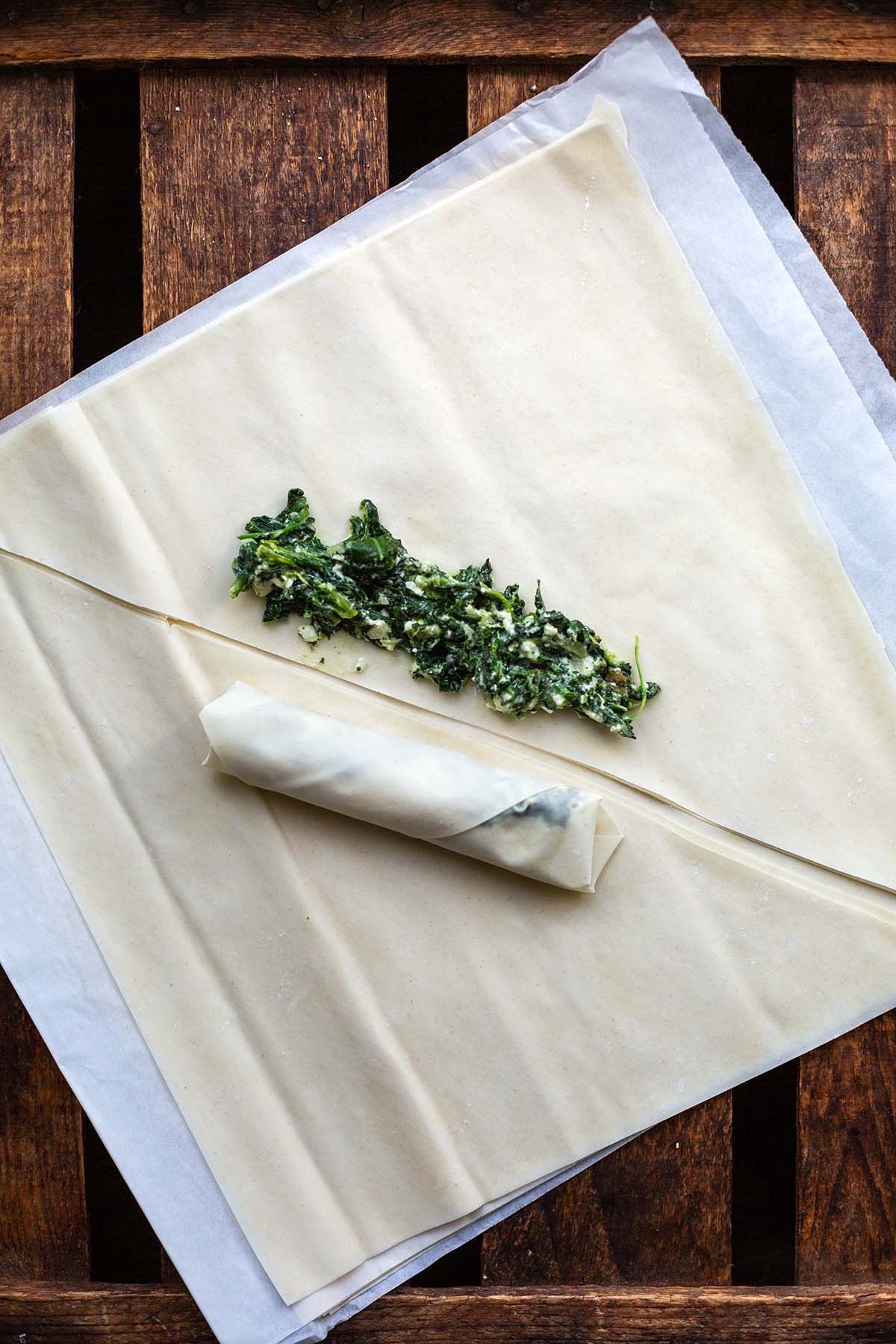 Gefülltes und gerolltes Börek und Yufkateigblatt, auf dem man die Füllung vor dem Zigarren rollen sieht