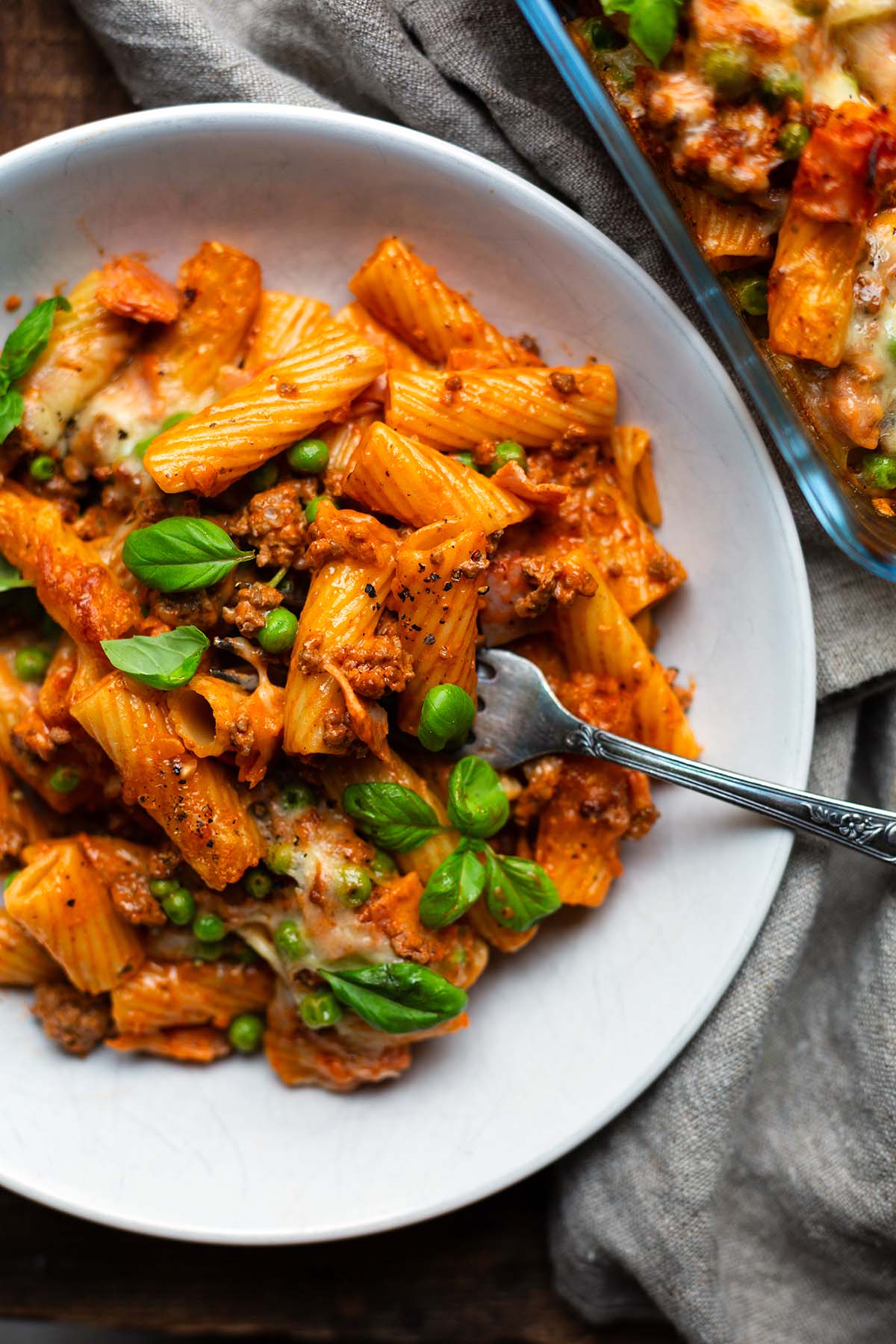Der fertige Rigatoni al Forno Auflauf auf einem weißen Teller angerichtet mit einer Gabel.