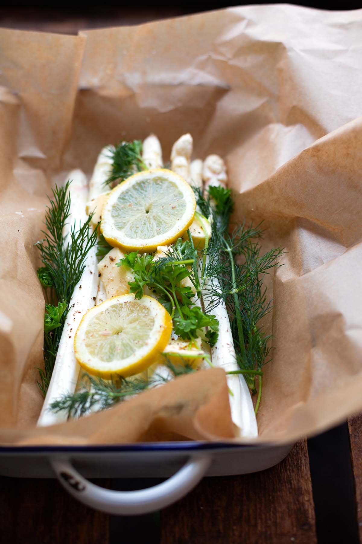 Weißer Spargel aus dem Backofen auf Backpapier, getoppt mit allen Zutaten vor dem backen.