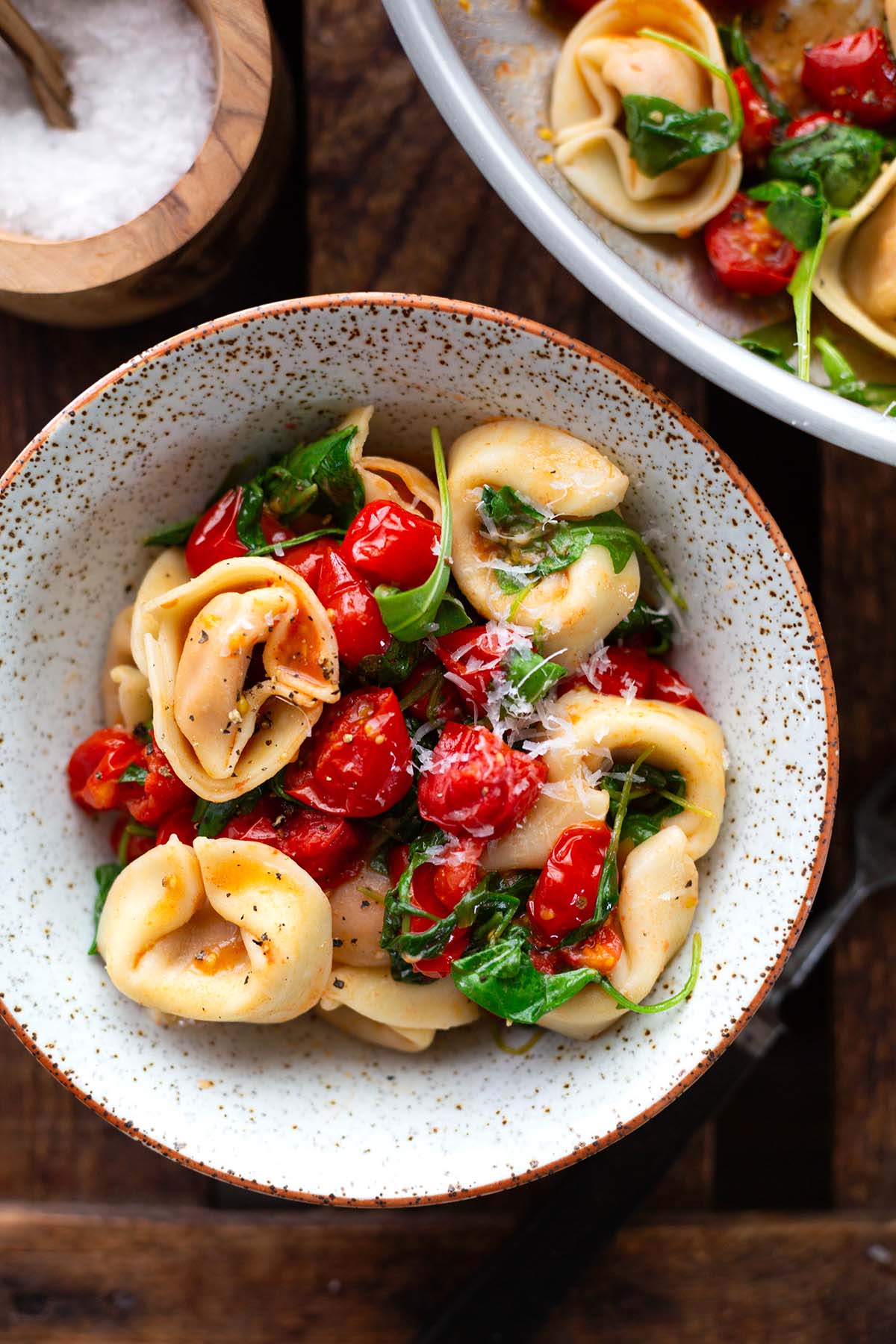 Vegetarische Tortellini-Pfanne mit Tomaten und Rucola in einer Schüssel. Bestreut mit Parmesan