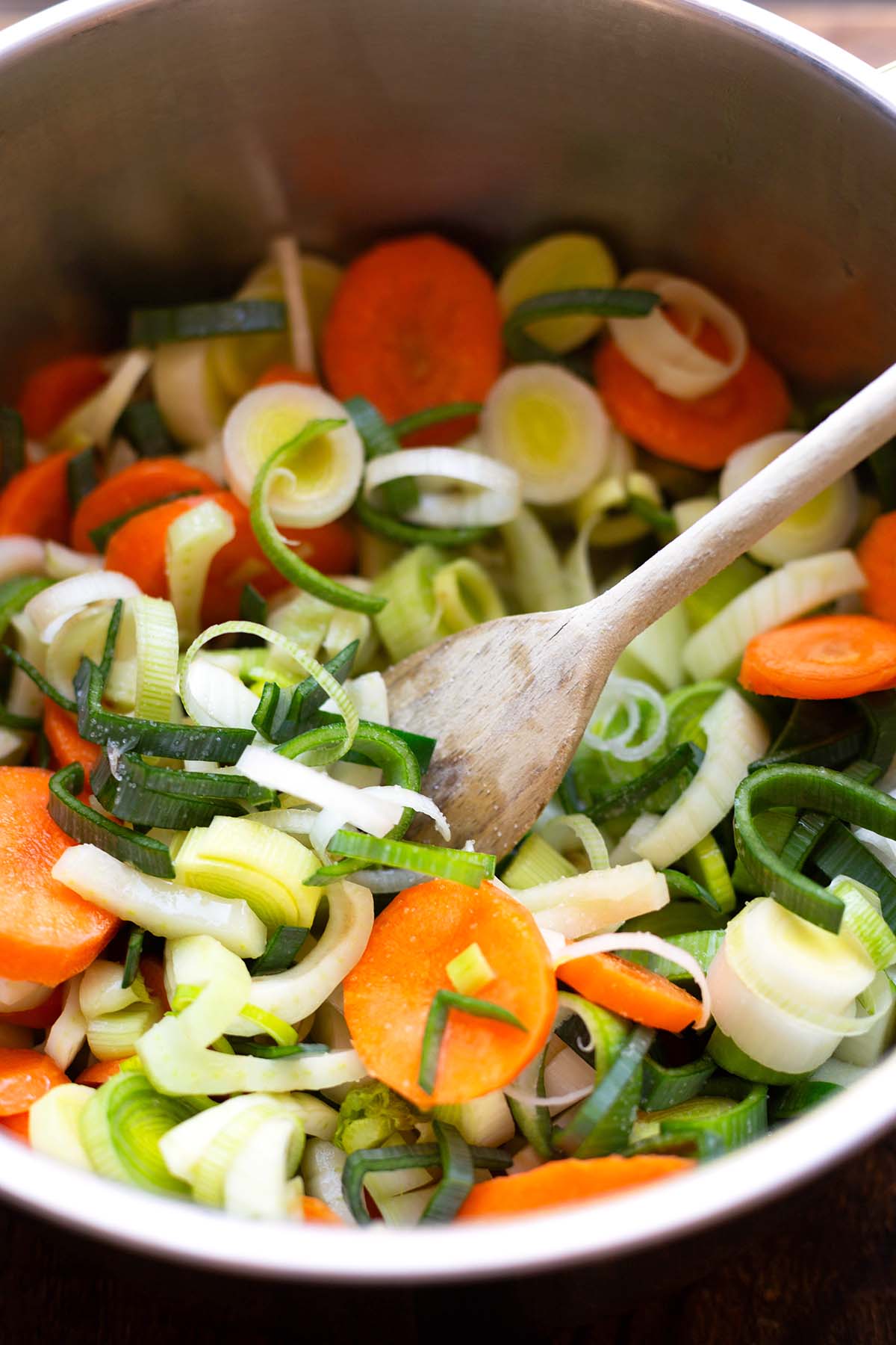 Gemüse für das Fischsuppe Rezept im Topf mit einem Kochlöffel