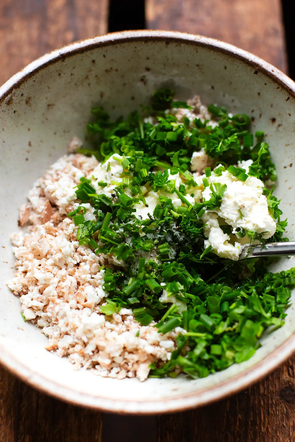 Die Füllung für die Champignons. Zu sehen sind kleine gehackte Pilzstiele, zerkrümelter Feta und gehackter Schnittlauch und Petersilie.