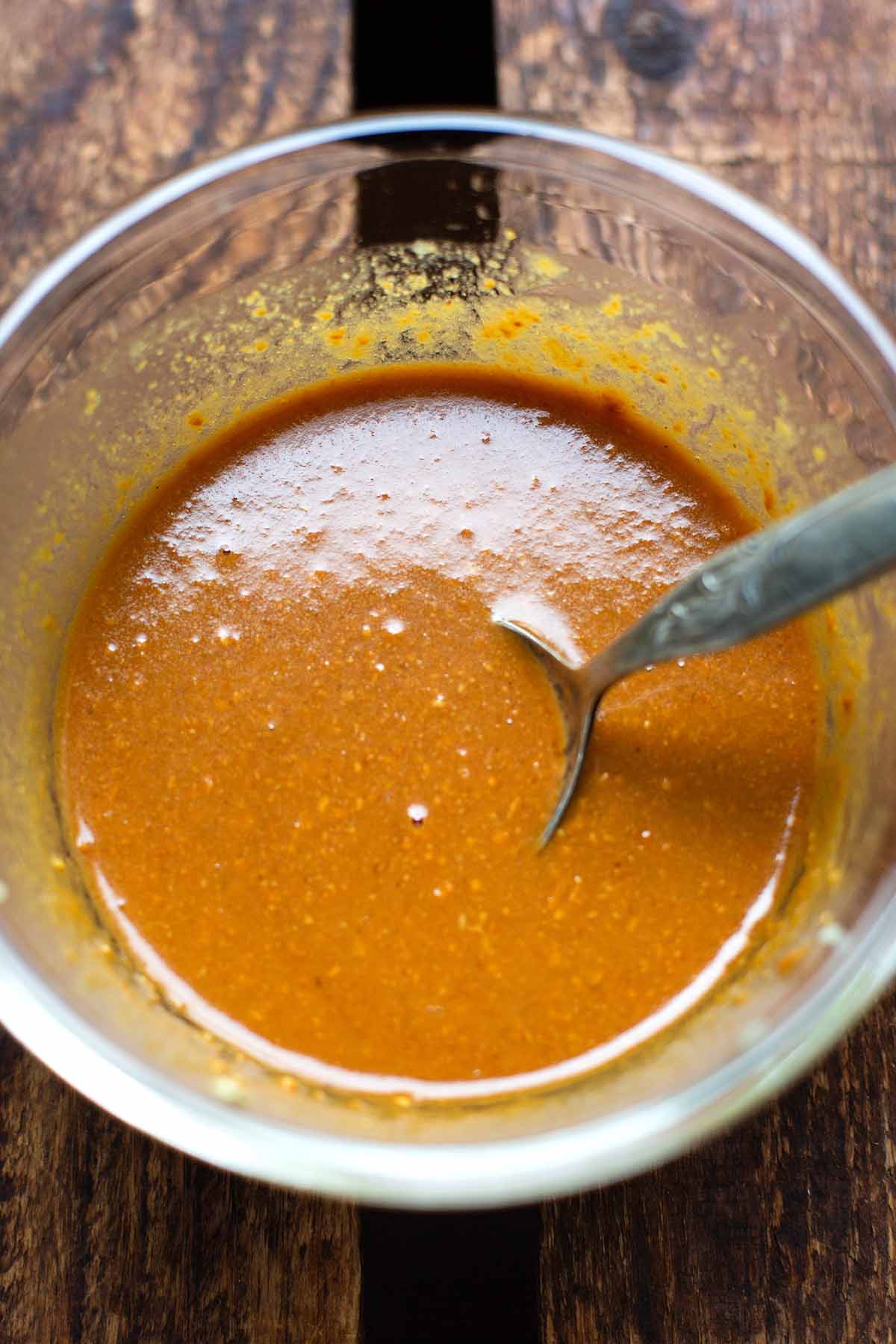 Erdnusssauce für asiatischen Nudelsalat in einer Schüssel. Mit Sojasauce, Reisessig, Limettensaft, Ahornsirup, Öl und Knoblauch.