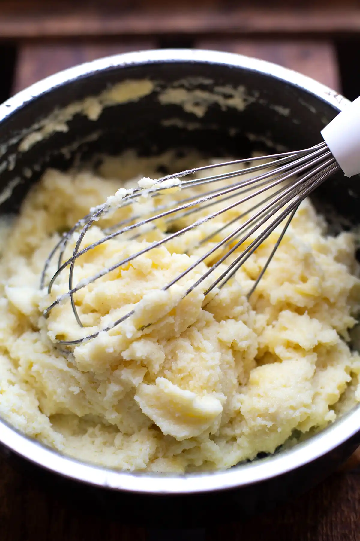 Angerührter Grieß für die Holundersuppe in einem schwarzen Topf. Ein benutzter Schneebesen lehnt noch in dem Grieß.