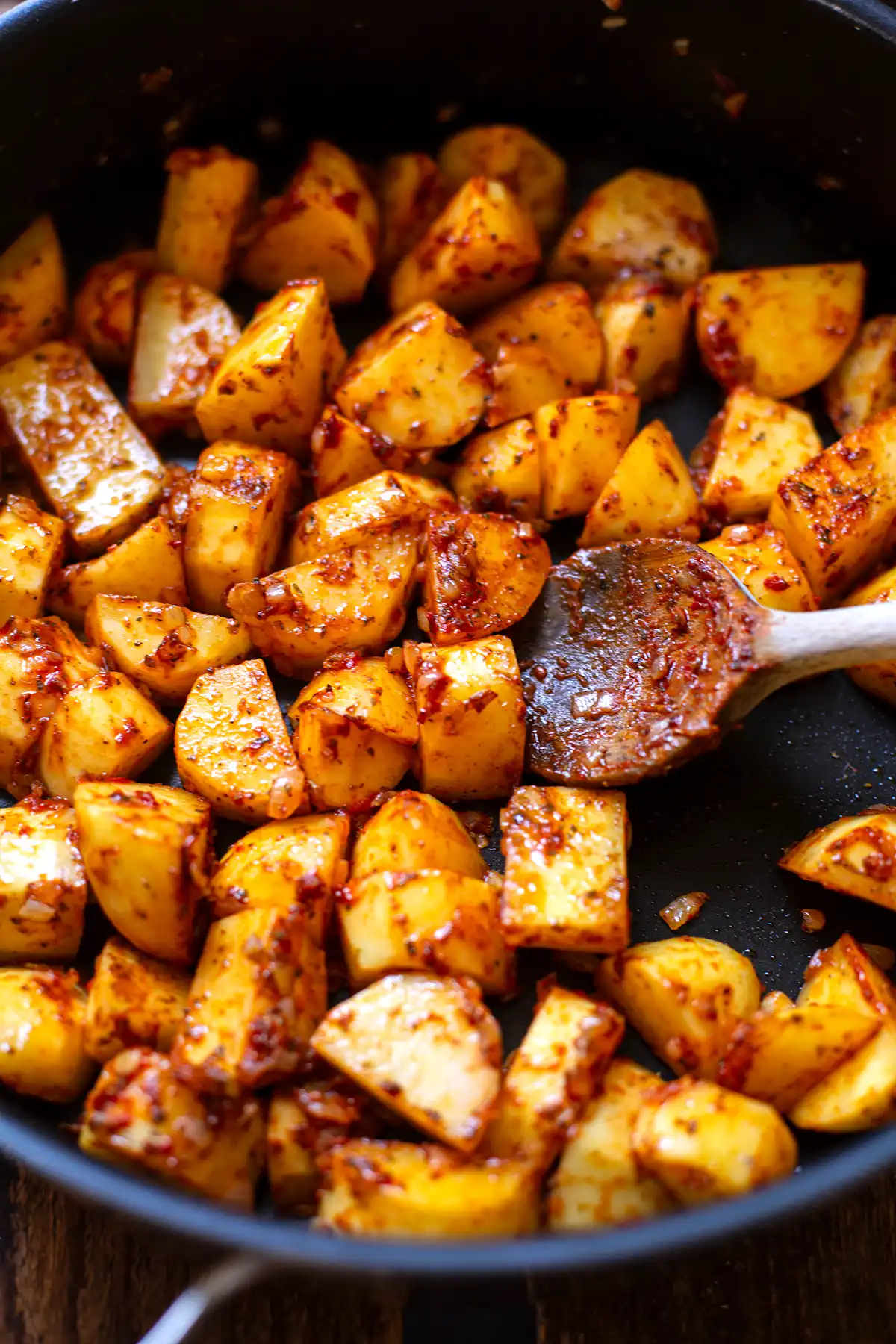 Klein geschnittene Kartoffeln werden in einer schwarzen Pfannen mit Zwiebeln, Knoblauch, Tomatenmark und Gewürzen angebraten und mit einem Holzlöffel gewendet.