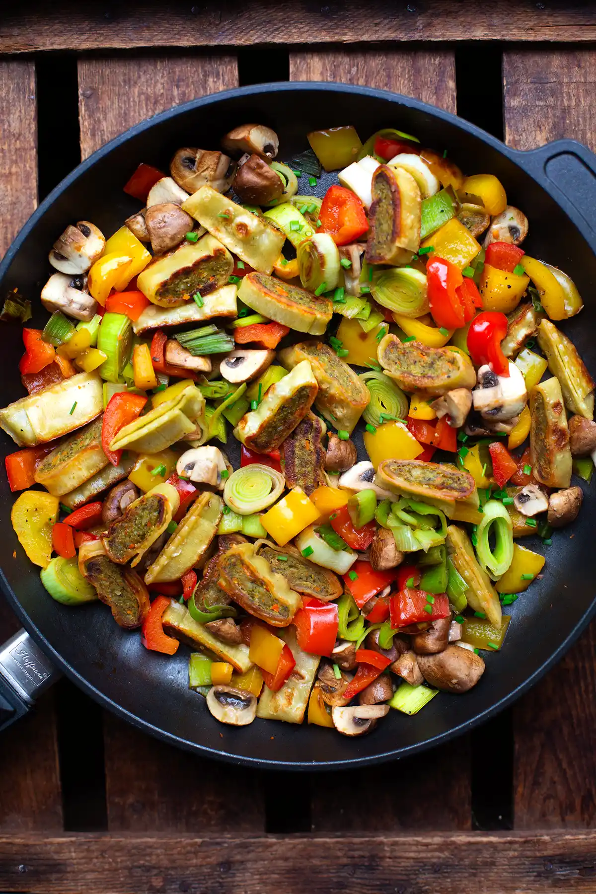 Fertige Maultaschen Pfanne mit Gemüse in einer schwarzen Pfanne.